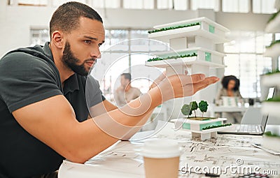 Young architect looking at 3D model. Professional architect planning a building project. Focused designer holding a Stock Photo