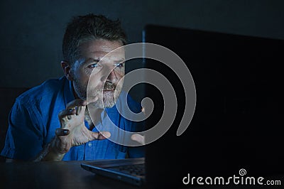 Young aroused and excited sex addict man watching mobile online in laptop computer light night at home in Stock Photo