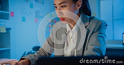 Young Asia cheerful professional woman sitting on desk focus concentrate working on laptop and digital tablet check detail final Stock Photo