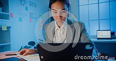 Young Asia cheerful professional woman sitting on desk focus concentrate working on laptop and digital tablet check detail final Stock Photo