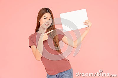 Young asia smiling woman holding advertising sign board and pointing finger. Isolated portrait on pink background with copy space Stock Photo