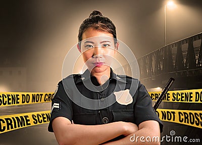 Young Asian American police officer standing serious in custody of crime scene for preserving evidence at do not cross police line Stock Photo