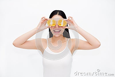 Young Asian beautiful smiling woman in black hair and white vest holding pieces of citrus oranges in fun and happiness emotion Stock Photo