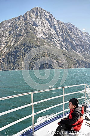 Asian boy looking at the mountains on a ferry trip in Milford Sound, NZ Stock Photo
