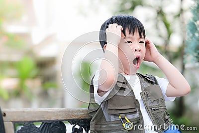 Young Asian boy sitting on the chair in the garden. Exploring the world, outdoor activity. Feeling confuse and sleepy Stock Photo