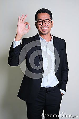 Young Asian business man smiling happy while giving OK finger sign Stock Photo