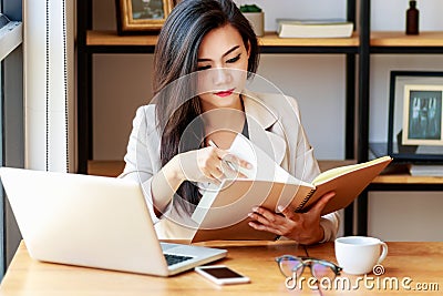 Young Asian business woman working at workplace. beautiful Asian woman in casual suit working with reading book, Stock Photo