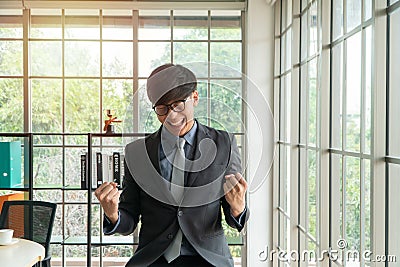 Young Asian businessman excited happy and celebrating success in the workplace after see finalizing the annual sales report. Conce Stock Photo