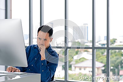 Young Asian businessman looking at the computer screen. His face Stock Photo