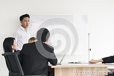 Young asian businessman present Board project to interested diverse colleagues at office negotiations Stock Photo