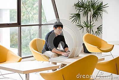 Young Asian businessman working on laptop in modern office. Stock Photo
