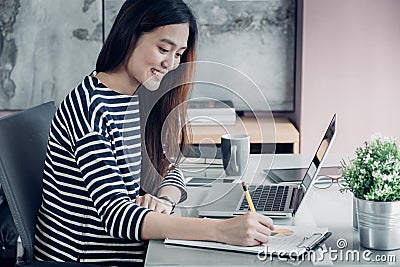 Young asian casual businesswoman writing report on office desk,work at home with online e-commerce job concept. Stock Photo