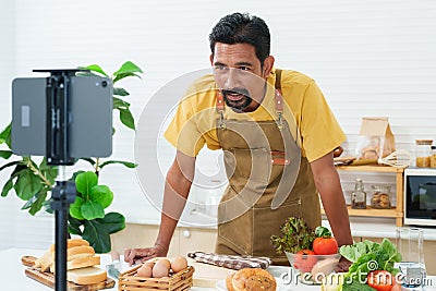 Young Asian chef who is good at cooking. love cooking Standing live via an online app and tablet in kitchen. Standing to talk and Stock Photo