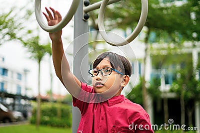 Young asian children hang on the monkey bar. To exercise at outdoor playground in the neighbourhood Stock Photo