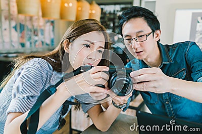 Young Asian couple learning to use mirrorless digital camera together at coffee shop Stock Photo