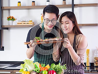 Young Asian couple looking at steak very happy after help to cooking a steak Stock Photo