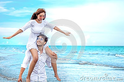 Young asian couple in love honeymoon at sea beach on blue sky. groom giving piggy back ride to bride . happy smiling wedding Stock Photo