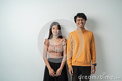 Young asian couple smiling while standing against Stock Photo