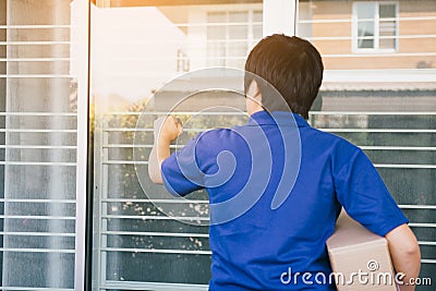 Young asian courier is using the hand of the knock at the door to deliver the goods Stock Photo