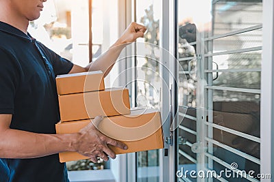 Young asian courier is using the hand of the knock at the door to deliver the goods Stock Photo