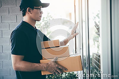 Young asian courier is using the hand of the knock at the door to deliver the goods Stock Photo