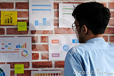 Young asian creative man reading and thinking about paper work on office wall with concentration, Working asia man reading Stock Photo