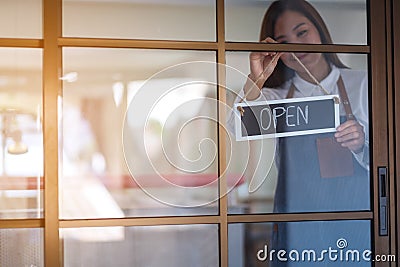 A young entrepreneur or a waitress hanging open sign on the shop front door Stock Photo