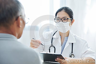 Asian Female Doctor talking to senior man patient. Stock Photo