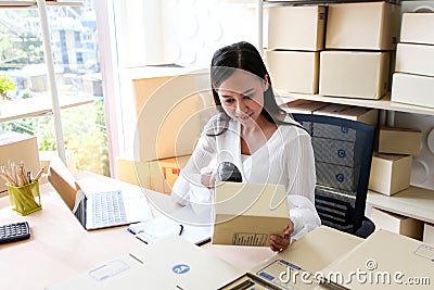 Young asian girl is freelancer Start up small business owner writing address on cardboard box at workplace,Shipping shopping Stock Photo