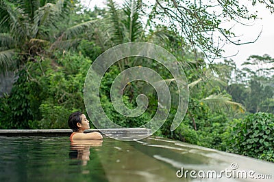 Young Asian Girl swimming in the infinity pool with beautiful view Stock Photo