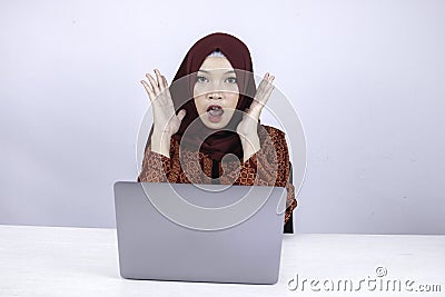 Young Islam woman wearing headscarf is shocked and excited with what she see on laptop on the table Stock Photo