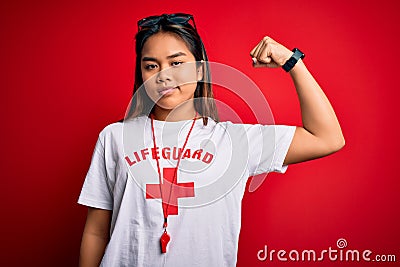 Young asian lifeguard girl wearing t-shirt with red cross using whistle over isolated background Strong person showing arm muscle, Editorial Stock Photo