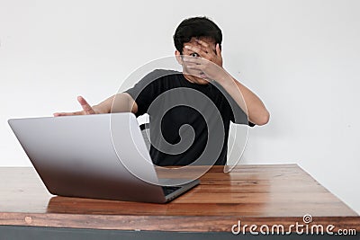 Young asian man hiding his face with hand because shocked and embarrassed by some porn videos or another forbidden thing he saw on Stock Photo