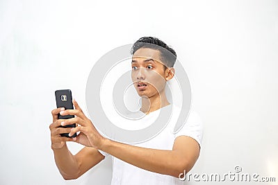 Young asian man holding smartphone and surprised by notification on his smartphone about discount or cash back from online shop Stock Photo