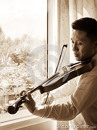 Young Asian man playing violin. Classical music instrument. Sepia color tone. Stock Photo