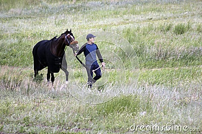 Young Asian man is walking with his pure breed Kazakh horse in Kazakhstan steppe Editorial Stock Photo