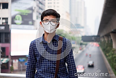 Young Asian man wearing N95 respiratory mask protect and filter pm2.5 particulate matter against traffic and dust city. Stock Photo