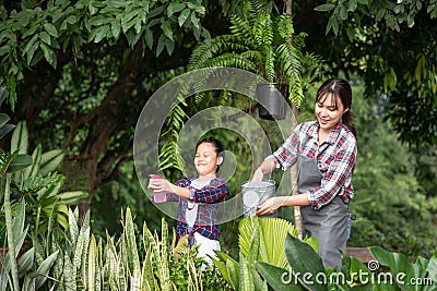 Young Asian mother and daughter happy working in the gardern together on weekend. Daughter helping mother watering Stock Photo