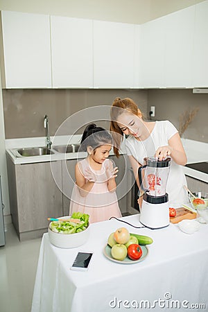 Young Asian mother and daughter making freshly squeezed tomato smoothies, daughter is very happy Stock Photo