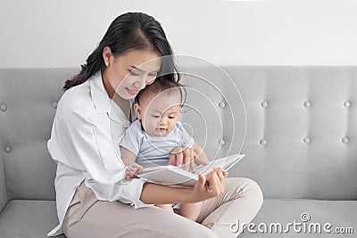 Young asian mother reading book to baby. Sweet moment. Stock Photo