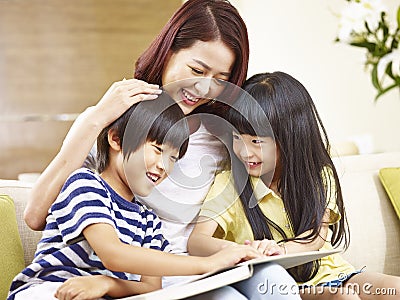 Asian mother reading story to two children Stock Photo