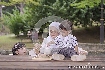 Young Asian mother teach her kids to saving money into piggy bank for better future. Stock Photo