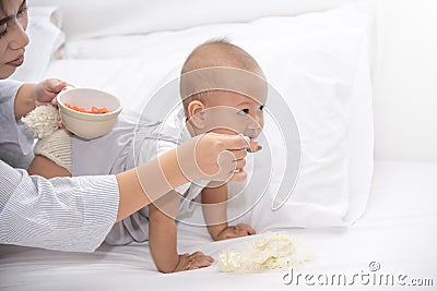 Young Asian mother tries to feed the food to baby girl. Daughter avoid food. Parent having a good time together during staying Stock Photo
