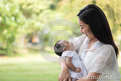 Young Asian mothers or single mom are smiling and carrying newborn babies. Family doing activities and relaxing in the park. Stock Photo