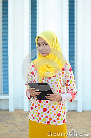 Young asian muslim woman in head scarf with mobile laptop Stock Photo