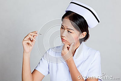 Young Asian nurse thinking look at thermometer Stock Photo