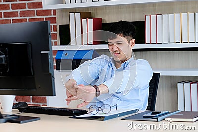 Young asian office man stretching body for relaxing while working with computer at his desk, office lifestyle, business situation Stock Photo