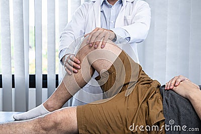 Young asian physiotherapist checking knee joint with injury to giving treatment Stock Photo