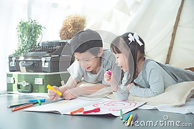 Siblings lying on the floor and drawing picture by crayon Stock Photo