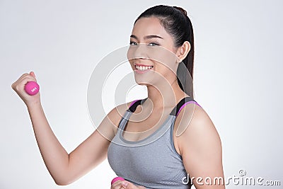 Young asian sporting woman training with dumbbell. Pretty athletic girl making physical exercise against white background. Health Stock Photo